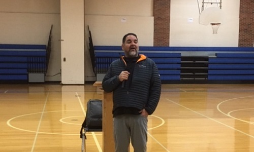 Ray speaking in gym to students