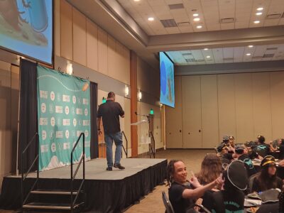 Presenter onstage leading a youth vaping workshop at a Florida conference with students seated in the audience.