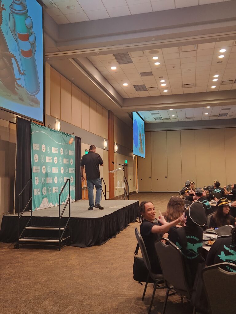 Presenter onstage leading a youth vaping workshop at a Florida conference with students seated in the audience.