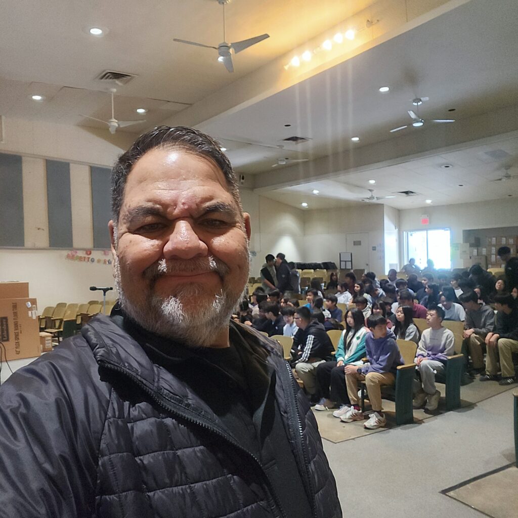 Ray Lozano presenting drug education to a middle school audience in an auditorium.