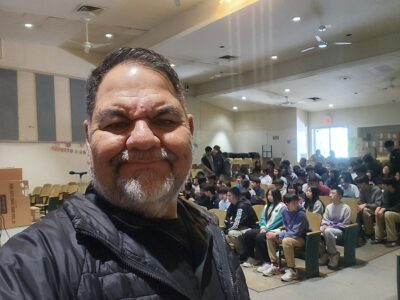 Ray Lozano presenting drug education to a middle school audience in an auditorium.