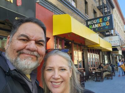 A couple smiling outside House of Nanking in San Francisco before Ray Lozano presents a youth drug prevention workshop at a local credit recovery program.