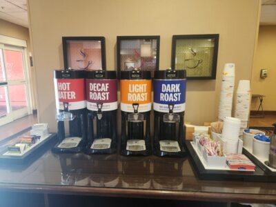 Coffee station at a hotel offering hot water, decaf roast, light roast, and dark roast, photographed by Ray Lozano while traveling to a youth prevention workshop.