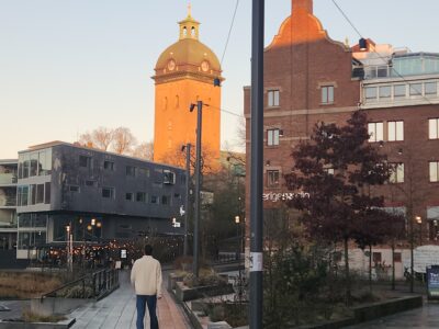 Early morning pedestrian walkway in a Swedish city, featuring historic brick buildings, a clock tower illuminated by winter light, and a calm urban setting.