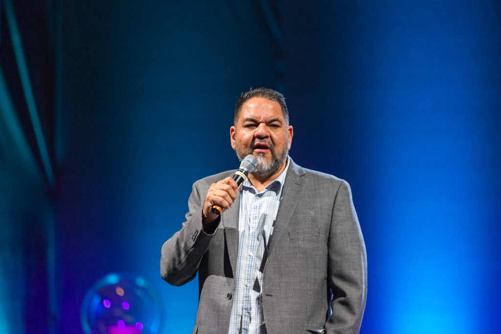 Youth drug prevention speaker delivering an evidence-based presentation on stage using a microphone.