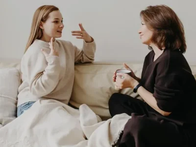 Parent talking with child at bedtime in a softly lit bedroom.