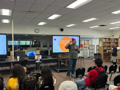 Ray Lozano presenting a youth drug prevention session to students in a school library while discussing how nicotine products are marketed to teens.